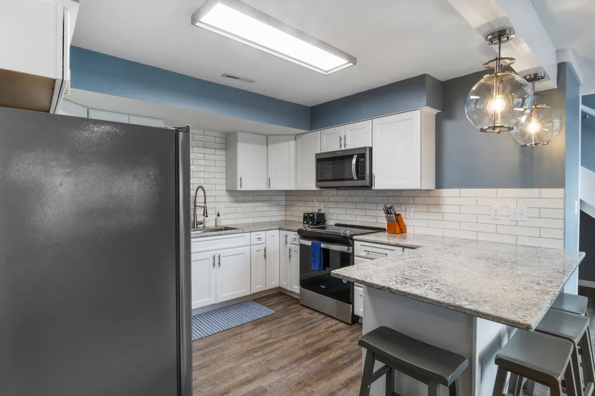 A modern, open kitchen with granite countertops, stainless steel appliances, and stylish subway tile backsplash. The space is well-lit with modern light fixtures and features an inviting, functional layout ideal for meal prep and entertaining.