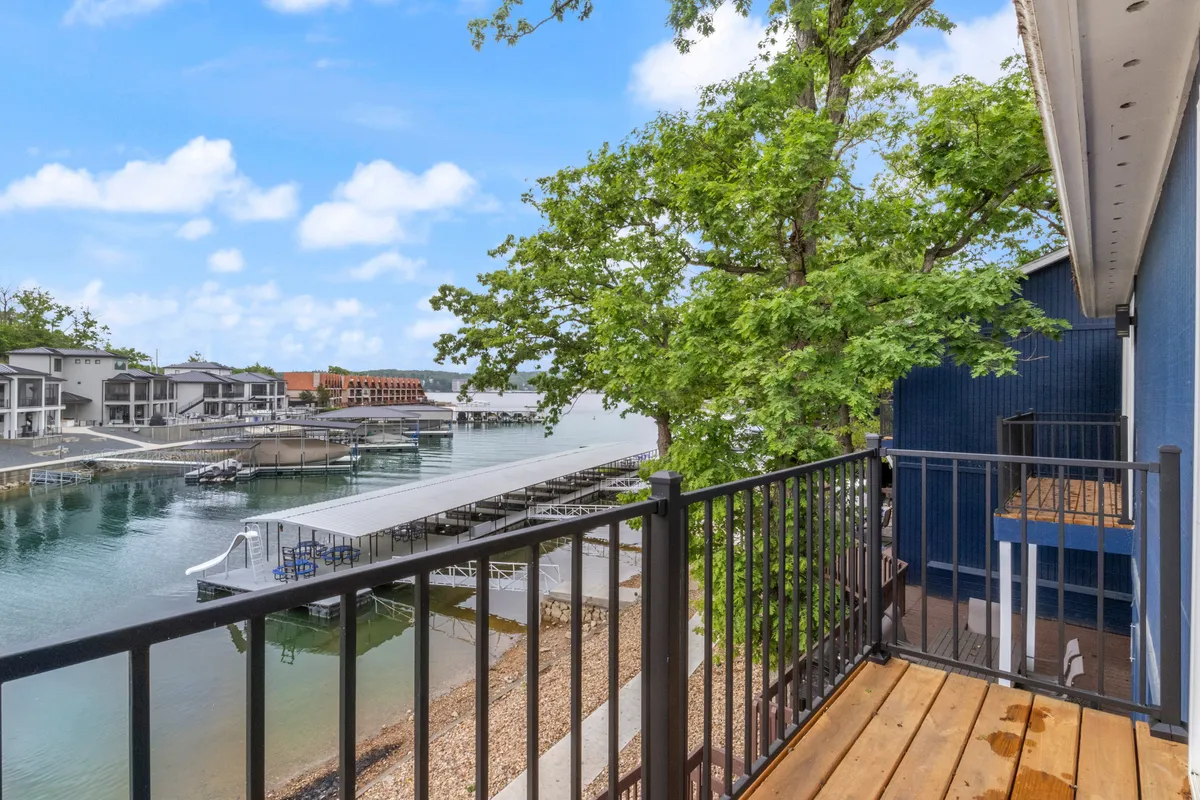 A tranquil exterior view showcasing the dock extending over the lake, surrounded by lush greenery. The dock is visible with ample space, providing direct water access and a serene lakeside setting perfect for leisure activities.