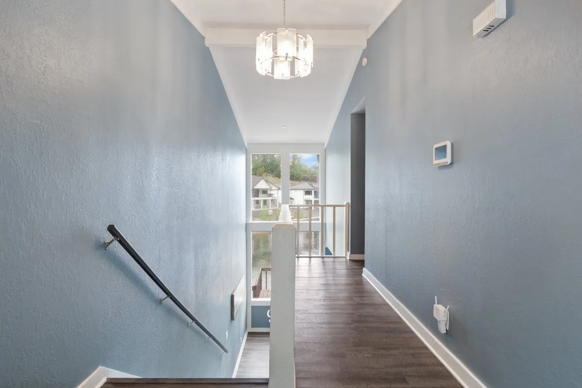 A bright and inviting interior entryway featuring a chandelier, stair railing, and large windows letting in abundant natural light. While inside, this image provides a sense of arrival and transition, suggesting easy movement between indoor comfort and outside adventures.
